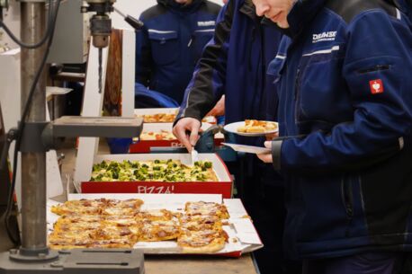 Die Mitarbeiter nehmen sich Pizza auf ihre Teller.